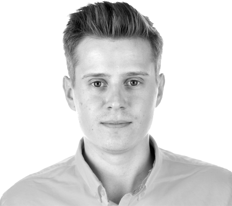 Black and white studio portrait of Michal Niemiec, Senior Product Manager, looking at the camera in a collared shirt.
