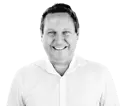 Smiling man, James Montgomery, in a white shirt, looking directly at the viewer with a friendly expression. He has short, dark hair and a light complexion, set against a plain white background for clarity.