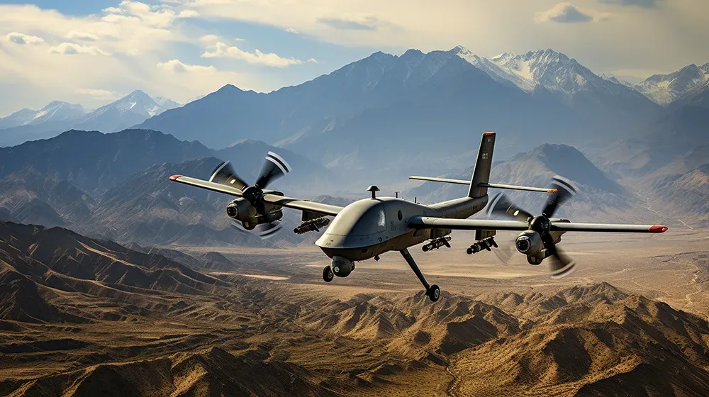 灰色の軍用ドローン2機が、曇り空の下、雪を頂いた山々を背景にした乾燥した山岳地帯を飛行している。ドローンは弾薬を搭載している。